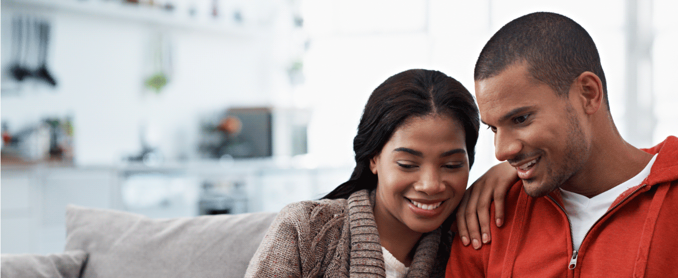 A young couple sitting on their couch reviewing their finances online