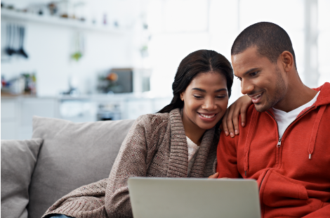 A young couple sitting on their couch reviewing their finances online