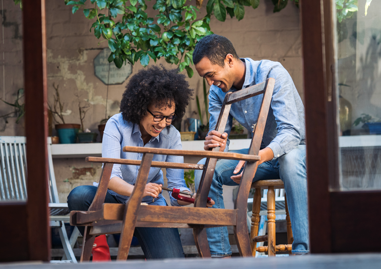 Smiling couple working together to restore a chair