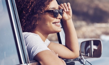 middle aged woman looking out a car window at the ocean