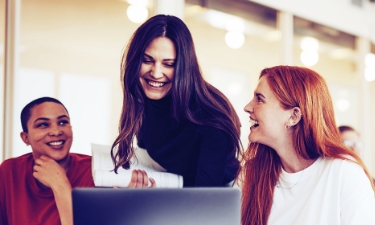 group of woman smiling and looking at a computer together