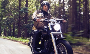 middle aged man on a motorcycle riding through the country side