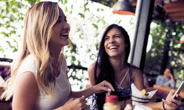 Two friends laughing together having lunch at a restaurant