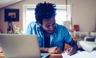 young student taking notes in his room