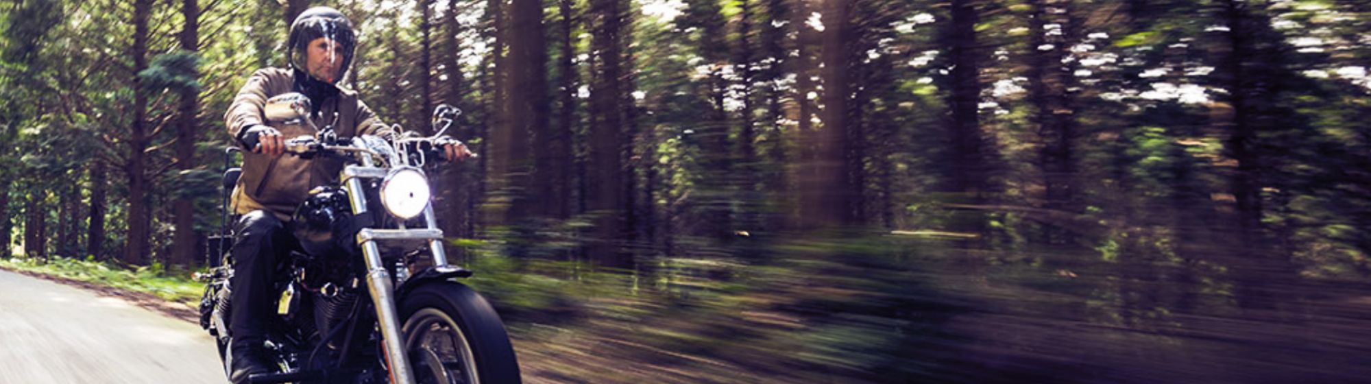 middle aged man on a motorcycle riding through the country side