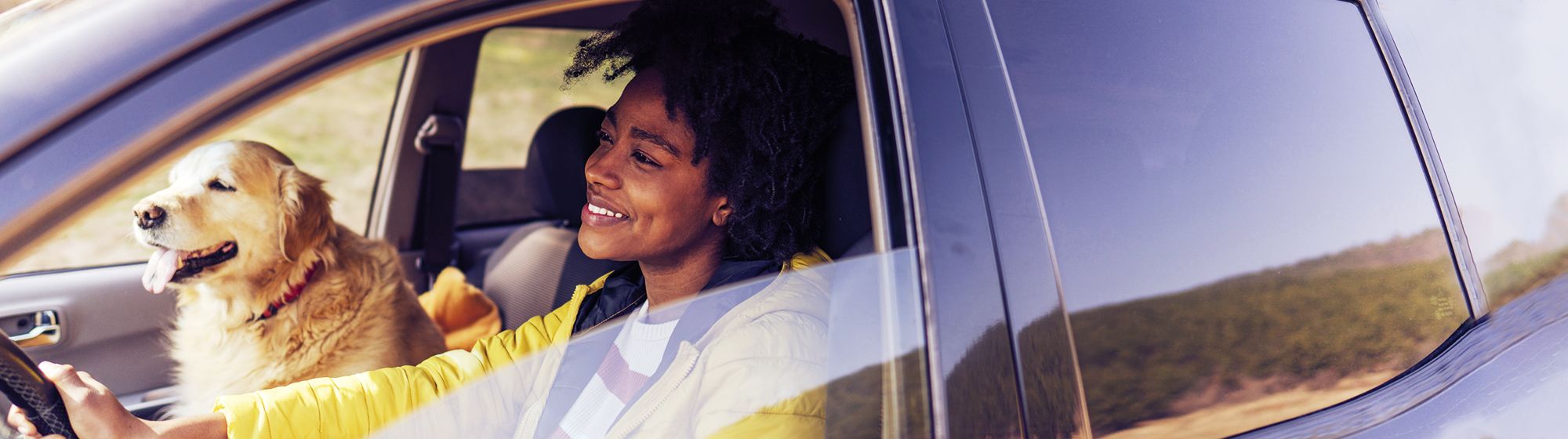 Young woman driving with her dog in the front passenger seat