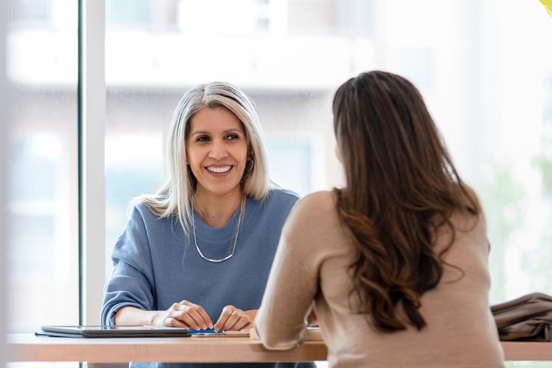 The adult woman sits with a financial advisor from the firm she is employed at.